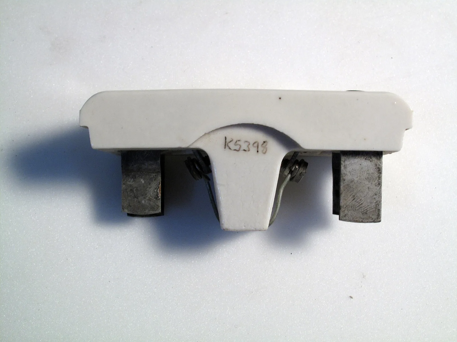 White ceramic two-pole fuse-holder body with exposed metal contacts and a central pull handle; representative historical fuse-holder family image, not a Mersen BFF63F2 photograph.